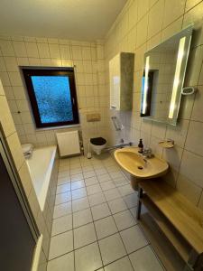 een badkamer met een wastafel, een bad en een raam bij Ferienhaus im Maadebogen in Wilhelmshaven