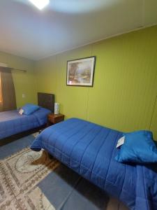 a bedroom with two blue beds and a green wall at Noface 3 in Los Vilos