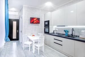 Una cocina con gabinetes blancos y una mesa y sillas blancas. en HB apartments Aghmashenebeli III, en Tiflis