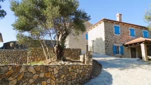 a stone wall with a tree in front of a building at Deluxe Nature Resort Galovi Dvori in Rab