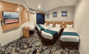una habitación con tres camas en una habitación con rocas en Kayan Al Raya Hotel Makkah by Moro, en La Meca