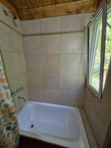 baño con bañera blanca y ventana en Cabaña Isla Coco en Tigre