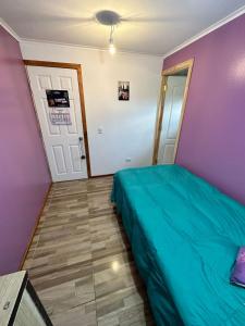 a bedroom with a green bed and a purple wall at Habitación con baño privado 
