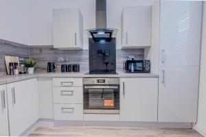 a kitchen with white cabinets and a stove top oven at Stunning Three Bedroom Townhouse In The Jewellery Quarter, Birmingham City Centre Sleeps 5- Free Parking in Birmingham