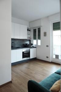 a kitchen with white cabinets and a blue couch at ComeCasa Città Studi Terraced Apartment in Milan