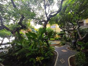 un jardín con árboles y plantas frente a un edificio en Sunshine Bungalows, en Amed