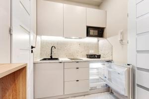 a white kitchen with a sink and a refrigerator at Tiny and cosy studio only 4 you in Katowice