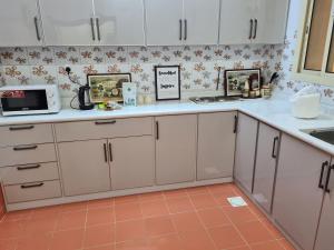 a kitchen with white cabinets and a microwave at Ayser 1 in Al Madinah