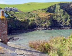 a house on a hill next to a body of water at Homestead in Port Isaac
