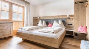 a bedroom with a bed with white sheets and pink pillows at Appartement Arnoldgut in Altenmarkt im Pongau