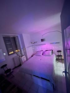 um quarto com uma cama branca e iluminação roxa em Jacuzzi au cœur de Bordeaux em Bordeaux