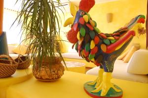 a colorful chicken statue on a table next to two plants at El Mosaico Del Sol in Lampedusa