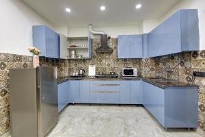 a kitchen with blue cabinets and a refrigerator at Limewood Stay Diamond 2BHK & Studio Huda City Centre & FORTIS in Gurgaon