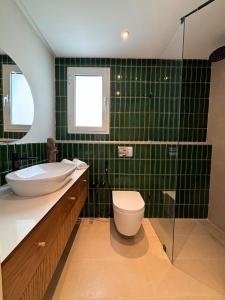 a green tiled bathroom with a toilet and a sink at Misk Villa - Boutique Hotel & Spa in Sidi Bou Saïd