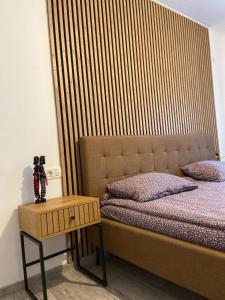 a bed with a wooden headboard next to a table at Rental house in Dumbrăviţa