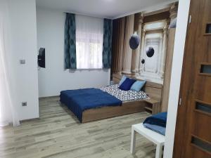 a bedroom with a bed with blue sheets and a window at Sweet Home Apartman in Balatonszárszó