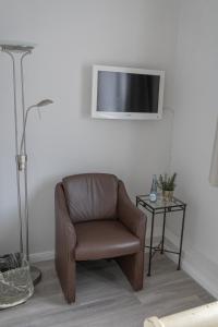 Cette chambre comprend une chaise brune et une télévision murale. dans l'établissement Hotel Seehof Norderney OHG, à Norderney