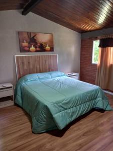 a bedroom with a bed with a green comforter at Cabañas LUNALUMA in Barrancas