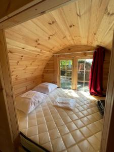 una camera con un grande letto in una casa di legno di TONNEAU HERBERGEMENT INSOLITE AU CAMPING DES NIERES a Ébreuil