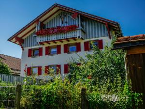 un edificio con un balcón con flores rojas. en Gästehaus Grath, en Lindenberg im Allgäu