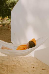 a woman sleeping in a hammock on a beach at Casa Modesta in Olhão