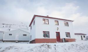 una casa blanca con puertas rojas en la nieve en Wilderness Center / Óbyggðasetur Íslands, en Óbyggðasetur