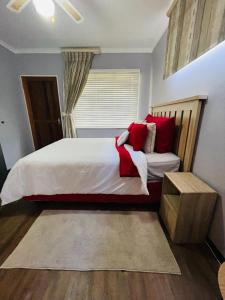a bedroom with a large bed with red pillows at The M-Pire Cottage in Bloemfontein