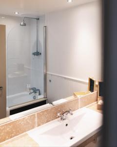 a bathroom with a sink and a mirror and a tub at Westmorland Hotel Tebay in Tebay