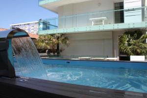 a swimming pool with a water feature in front of a building at Apartments in Lignano 21707 in Lignano Sabbiadoro