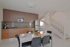 eine Küche mit einem Tisch mit Stühlen und einer Treppe in der Unterkunft Apartments in Lignano 21702 in Lignano Sabbiadoro