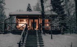 una cabaña en el bosque con nieve en las escaleras en Annas Dzirnavas, en Annas