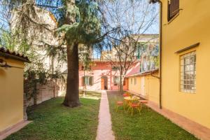 einen Garten mit einem Tisch, Stühlen und einem Baum in der Unterkunft [Piazza Maggiore] Il Sentiero - Villa with garden in Bologna