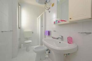 Baño blanco con lavabo y aseo en Apartments in Lignano 21597, en Lignano Sabbiadoro