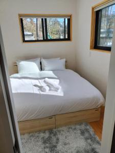 a bedroom with a bed with white sheets and a window at Nestle Inn Hakuba in Hakuba