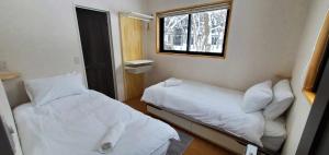 a small room with two beds and a window at Nestle Inn Hakuba in Hakuba