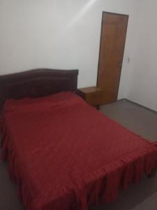 1 dormitorio con cama roja y cabecero de madera en Casa el tala en Villa Santa Cruz del Lago