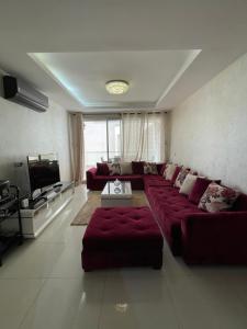 a living room with a red couch and a television at Superbe appartement pieds dans l’eau in Aourir