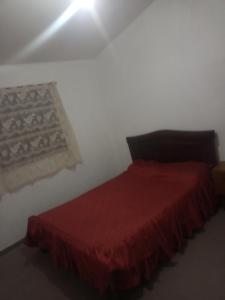 1 dormitorio con 1 cama con colcha roja en Casa el tala en Villa Santa Cruz del Lago