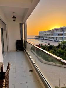 a balcony with a view of the beach at sunset at Superbe appartement pieds dans l’eau in Aourir