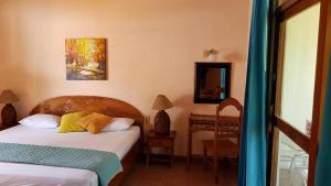 una camera con 2 letti, una scrivania e uno specchio di Samara Beach Hotel a Sámara