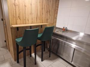 a kitchen with two green chairs next to a sink at Gent Apt in Vienna