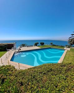 a swimming pool with the ocean in the background at La Marina home in Concón