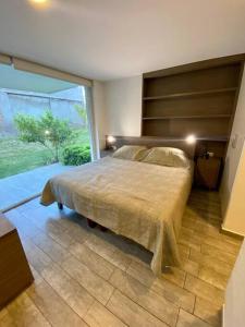 a bedroom with a bed and a large window at Moderno y equipado estudio en Los Dominicos in Santiago