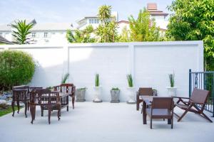 een patio met tafels en stoelen en een witte muur bij Singharaj Boutique Hotel in Chiang Mai