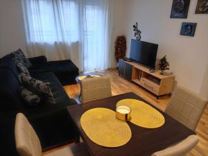 ein Wohnzimmer mit einem Tisch und einem TV in der Unterkunft Apartman Pan in Sokobanja