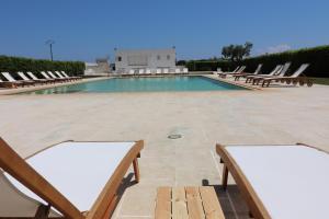 una piscina con sedie a sdraio e un mucchio di cose di Casa Primitivo di Manduria residence Torre Santo Stefano Otranto ad Alimini