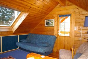 ein Wohnzimmer mit einem blauen Sofa in einem Blockhaus in der Unterkunft véritable chalet finlandais in Basse-sur-le-Rupt