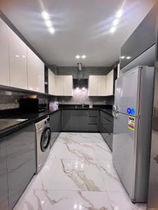 cocina con armarios blancos y nevera en شقه فندقيه مستقله بالشيخ زايد en Sheikh Zayed