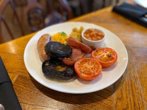 a plate of food with sausage and tomatoes on a table at The Fishmongers Tavern in Sheringham