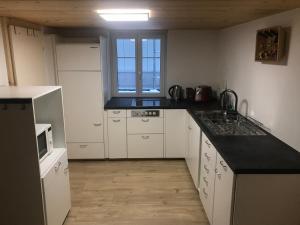 een keuken met witte kasten en een zwart aanrecht bij Bijou 2 hübsche 1 Zimmer Wohnung in Herisau